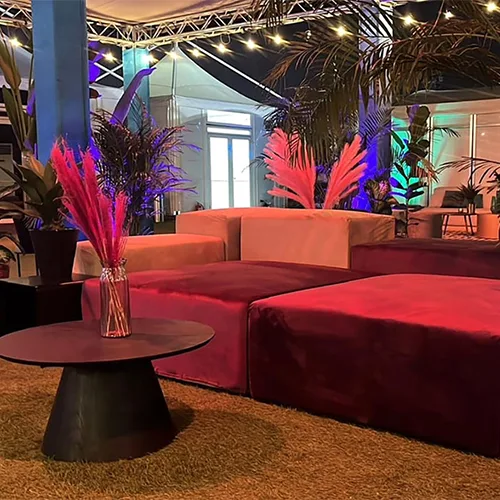 Layered lounge environment featuring armchairs, rattan seating, rugs and natural timber tables