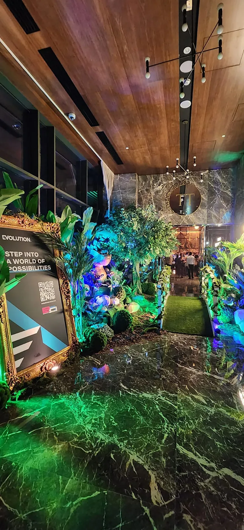Gold hospitality furniture paired with feature greenery for a sophisticated temporary event interior.